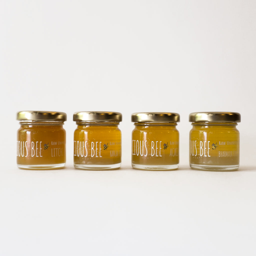Four jars of 'Licious Bee' honey lined up on a white background
