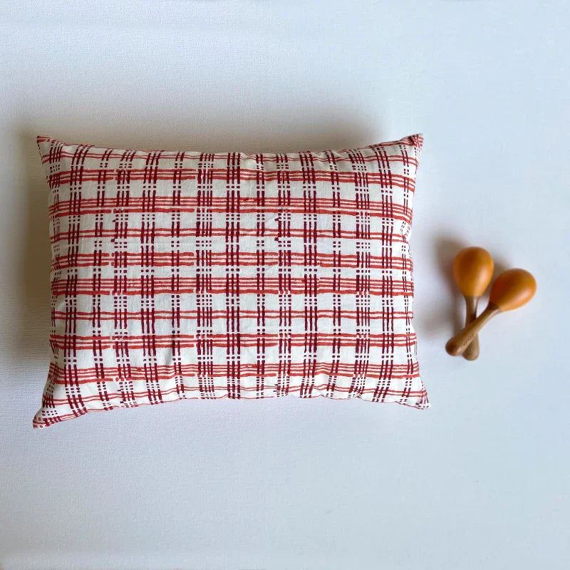 Red and white checkered pillow with wooden toys on a light blue background