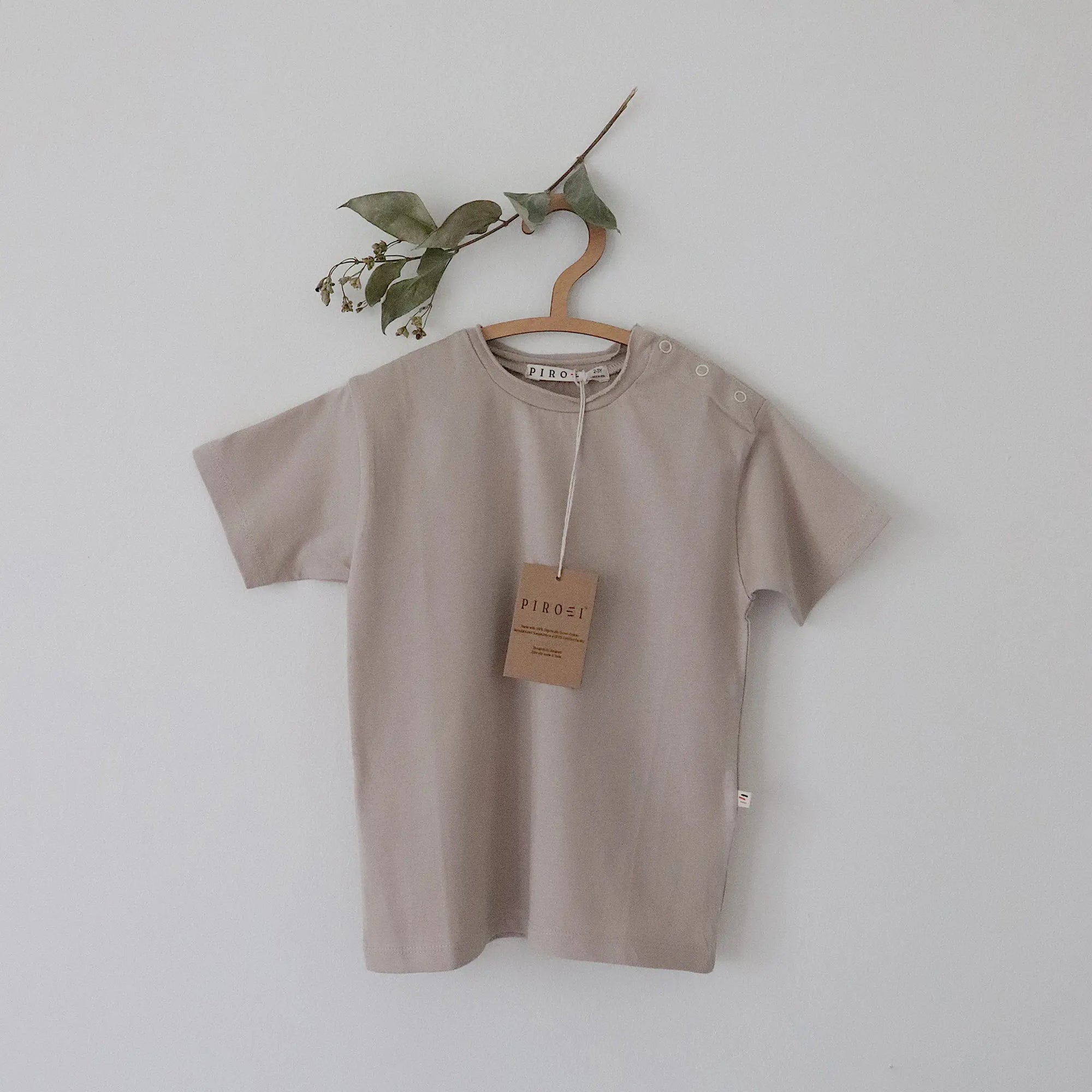 Beige t-shirt on a hanger with a tag against a plain background