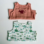 Two children's vests, one pink with a fish design and one green with fish pattern, on a light gray background.