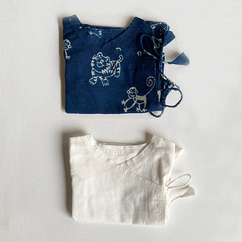 Folded blue and white children's clothing with animal prints on a light gray background